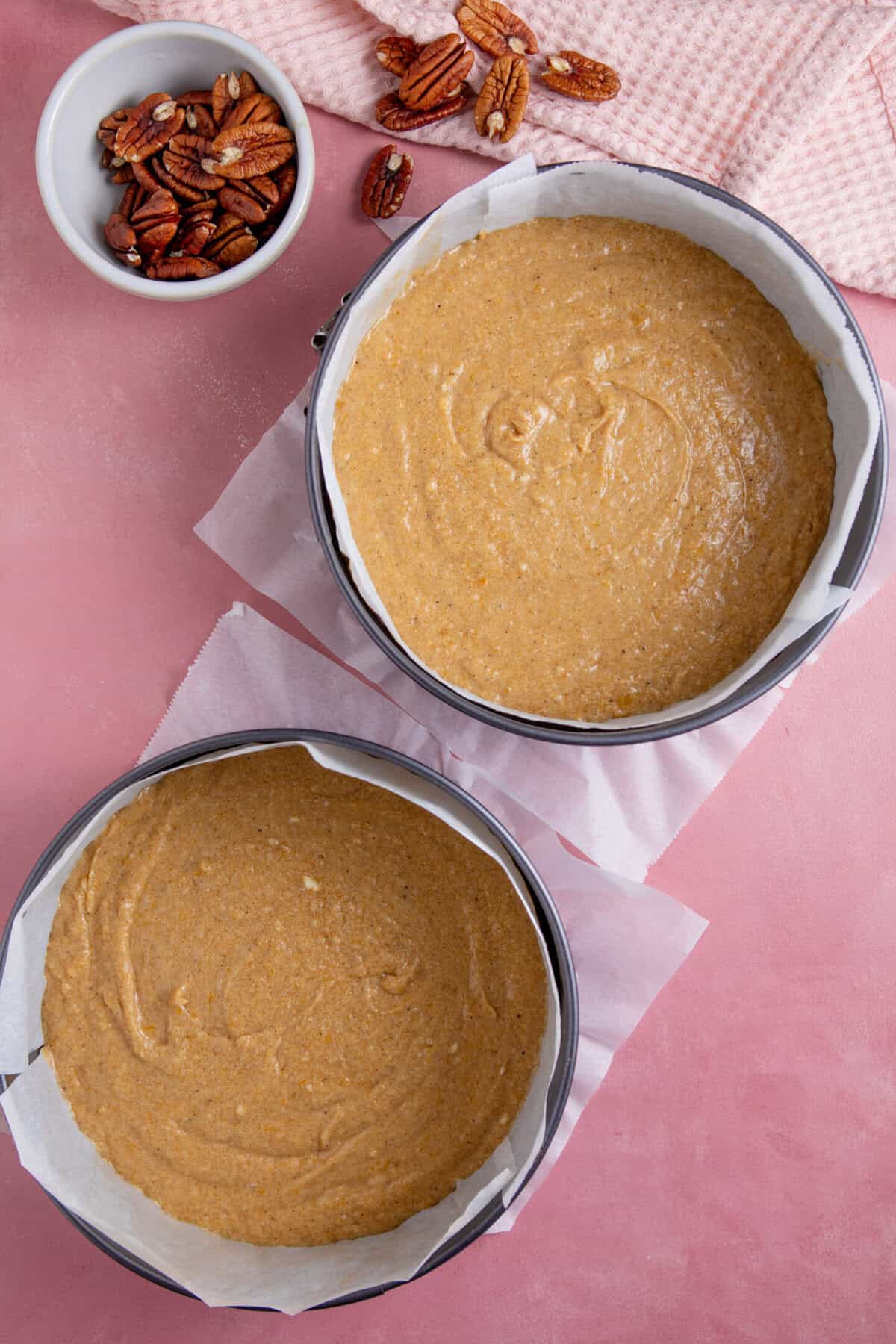 Process shot for a pumpkin spice latte cake showing the batter divided between two cake tins.