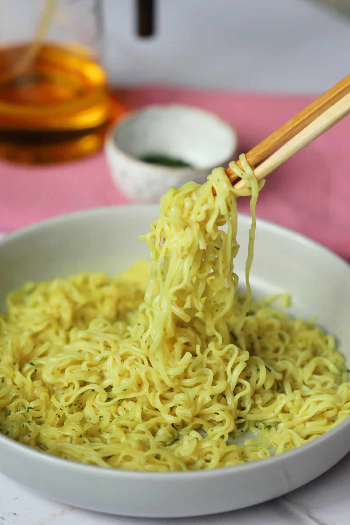 Chopsticks lifting gluten free noodles out of a bowl.