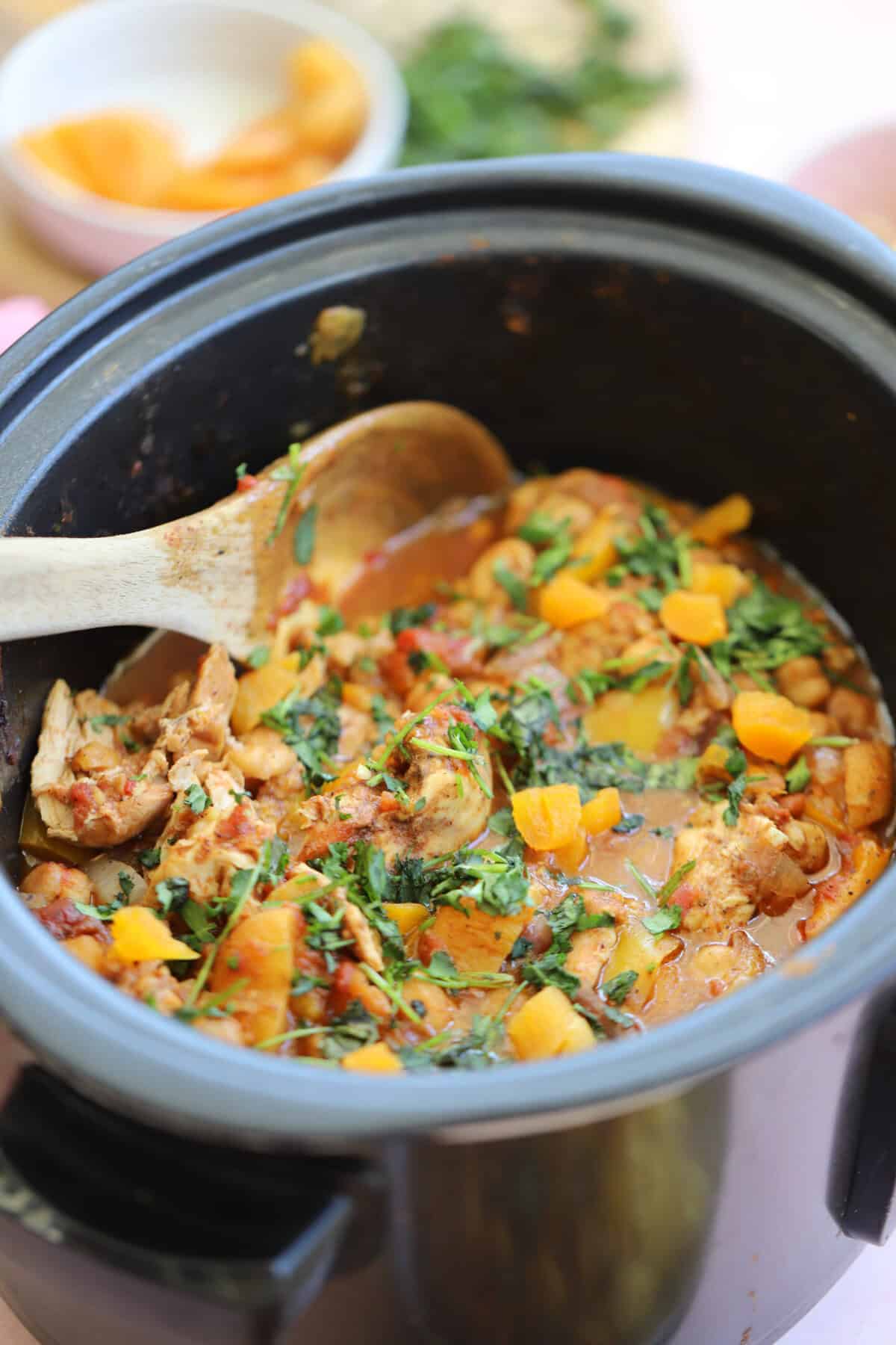A slow cooker filled with chicken tagine and sprinkled with fresh coriander.