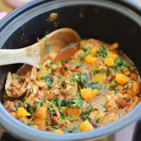 A slow cooker filled with chicken tagine and sprinkled with fresh coriander.