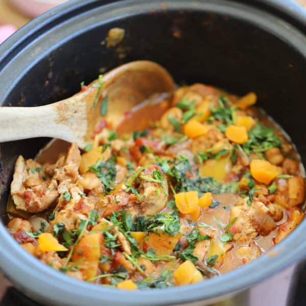 A slow cooker filled with chicken tagine and sprinkled with fresh coriander.