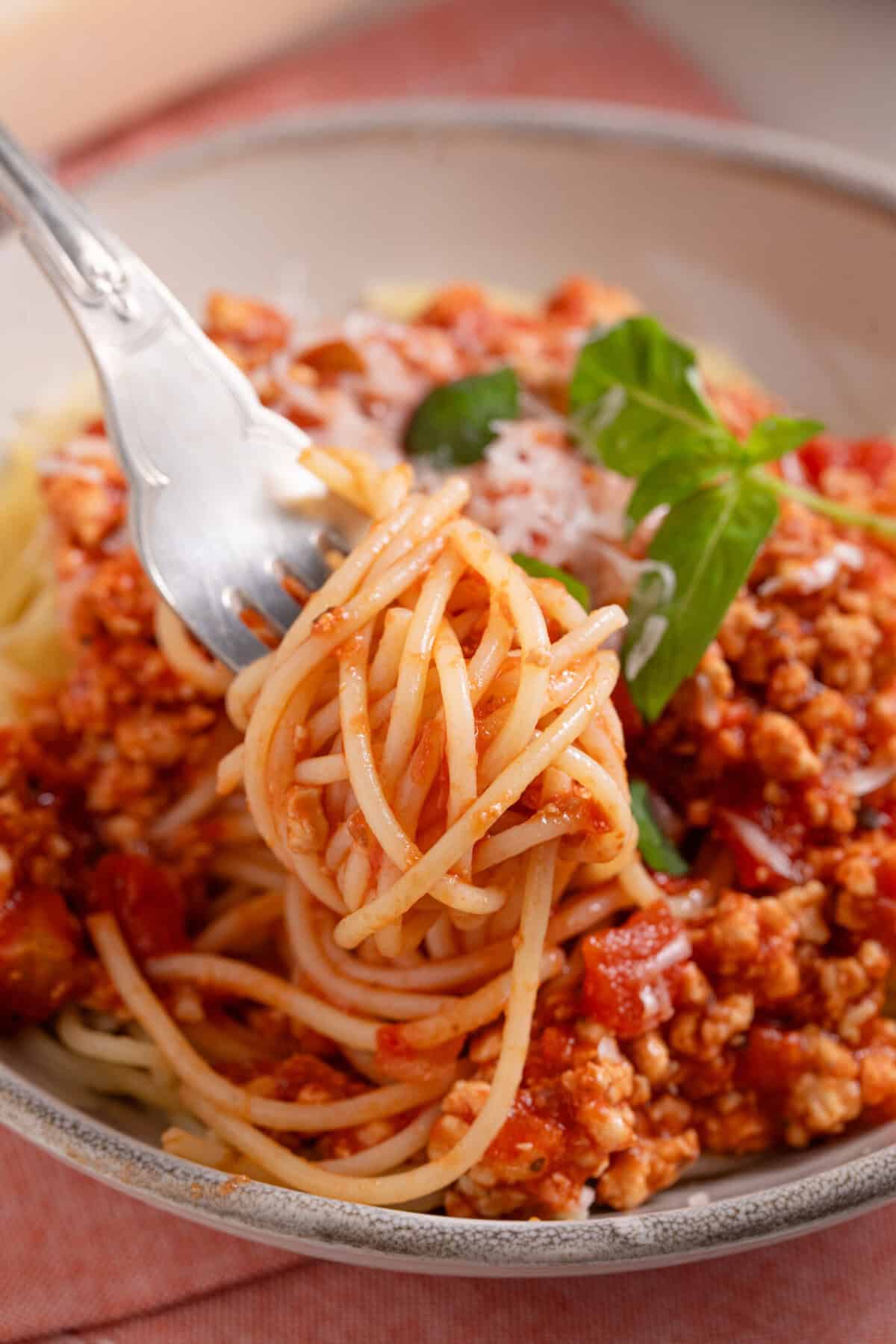 Close up of a fork swirled with gluten free turkey spaghetti bolognese.